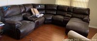 Full view of four-piece dark brown faux leather sectional sofa showing overall structure and wear.