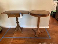 Both wood side tables shown side-by-side against a wall: rectangular pedestal table with leaves extended and round table with leather-like inset top.