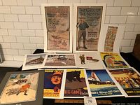 Overview of 15 Canadian prints laid out on table including posters of Northern Ontario Farm Lands, Canadian Pacific, and other Canadian art posters.
