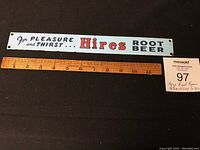 Full view of Hires Root Beer enamel advertising sign with wooden ruler for size reference.