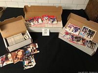 Wide view showing boxes filled with stacked hockey cards along with loose cards spread out representing the lot.