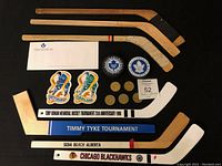 Full lot containing 7 mini hockey sticks, business envelope, 2 hockey pucks, 5 metal coins, and 2 cloth crests