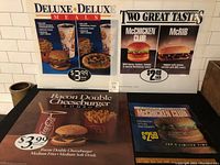 Four McDonald's restaurant advertising signs arranged on a table showing images of burgers, fries, pizza, and drinks with pricing from the 1990s.