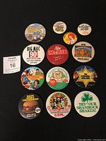 Top-view photo of all 13 McDonald's employee pins arranged on black background, clearly showing text and graphics of each pin.