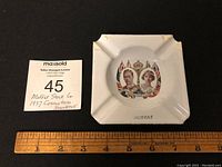 Full view of the square enamel ashtray next to a ruler showing dimensions approximately 3 inches square.