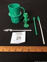 Full lot of Mr. Peanut plastic collectibles including mug, salt shaker, straw and two stir sticks on black background with measuring scale.