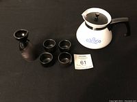 Full lot overview showing the 5-piece saki set arranged next to the Corning Ware teapot on a black surface.