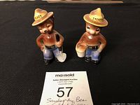 Pair of Smokey the Bear salt and pepper shakers on black surface with auction card
