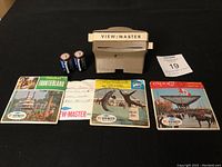 Viewmaster viewer, three sets of reels in cardboard sleeves (Disney Frontierland, Expo67, Marineland of Florida), two Panasonic batteries, lot tag in image