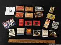Photo showing all 20 match packages arranged on black background with ruler for scale