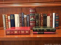Photo showing 23 hardcover books featuring classic literature organized on wooden shelf; spines display various titles and authors including Steinbeck, Tennessee Williams, Shakespeare, and others