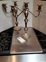 Pair of three-arm silver-plated candelabras displayed on a kitchen stove top.