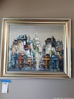 Front view of the framed abstract cityscape artwork prominently featuring buildings and a domed structure.
