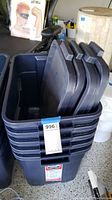 Stack of six large dark blue plastic storage tubs with lids placed vertically on top, showing the handles and structure of lids and tubs.