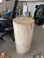 Full side view of cylindrical stone mosaic pedestal in garage setting