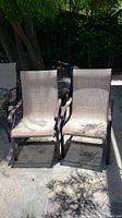 Photo of two outdoor patio chairs side by side in sunlight on a patio surface