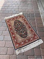 Full view of vintage Turkish carpet rug laid on stone floor showing overall pattern, colors, and fringes.