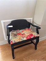 Full view of the vintage bench chair with black painted wood frame and floral upholstered seat, showing design and proportions.