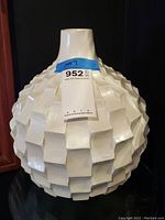 Front angle of the white painted wooden vase showing the carved raised square pattern and narrow neck.