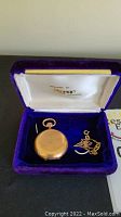 Pocket watch and gold chain in a purple velvet and satin-lined presentation box