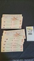 Three sets of crisp, sequential 1986 Canadian $2 bills displayed in overlapping stacks showing serial numbers.