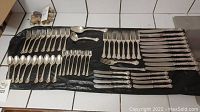 Full layout of forks, spoons and knives on black mat