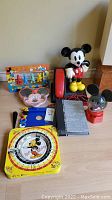 Photo showing entire collection including Mickey Mouse rotary phone, photo album, game dial, toys, plates, and pen