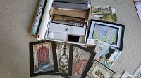 Overview of various framed prints, cards, rolled poster and other printed art items spread on floor.