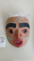 Front view of mask showing overall painted design and feather trim