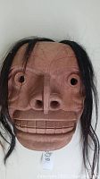 Front view of mask showing full carved face and hair strands