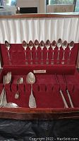 Red velvet-lined wooden chest opened showing flatware arranged in slots