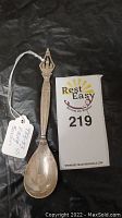Full view of the Georg Jensen sterling silver spoon paired with a business card for scale.
