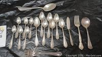 Full group shot of 17 sterling silver flatware pieces displayed on black background