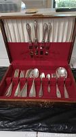 Opened wooden chest showing red velvet-lined slots holding flatware