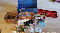 Photo showing a collection of items including the tool box contents, coins, vintage phone, baskets, and small vintage containers, laid out on a light wood floor.