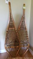Pair of wooden snowshoes leaning against wall showing overall shape and size