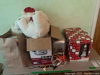 Lot contents including white Coca Cola mini cooler, cardboard box with Pillsbury Doughboy decoration, Coca Cola lava lamp in box, and small decorations on table.