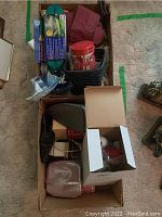 Overview of box contents showing iron, garden hose, lidded tin, and bags