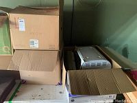 Three cardboard boxes stacked and arranged, showing packed kitchen appliance and storage items.