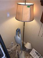 Full view of the metal and stone floor lamp with beige fabric lampshade, white ceramic table lamp, and flexible adjustable floor lamp all grouped near the wall outlet with cords visible.