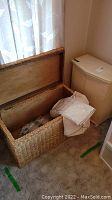 Open wicker chest showing interior and items stored inside. Hinged wooden lid visible.