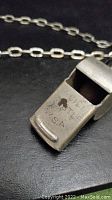 Close-up photo showing antique metal whistle with the engraving 'LICI CASTLE U.S.A.'