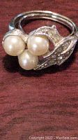Close-up of Avon ring with three faux pearls and rhinestone accents on a silver-tone leaf design