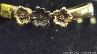 Close-up photo showing three flower decorations on the brass cuff bracelet.