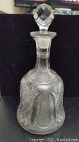 Full view of the crystal decanter with stopper on top, showing overall shape and clarity.