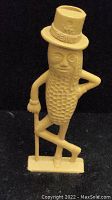 Front view of beige Mr. Peanut figurine whistle, showing detailed peanut shell texture, facial features, and text on the top hat.