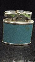 Photo of lighter front showing blue enamel body and silver metal top with ignition mechanism.