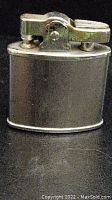 Full view of vintage silver-tone metal table lighter showing body and ignition mechanism
