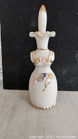 Side view of vintage white glass perfume bottle with floral decorations and gold accents