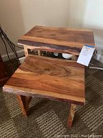 Two natural wood nesting tables stacked, showing live edge wooden tops and sturdy legs.
